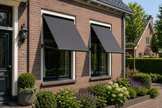 Twee antraciet uitvalschermen boven de ramen van een bakstenen woning